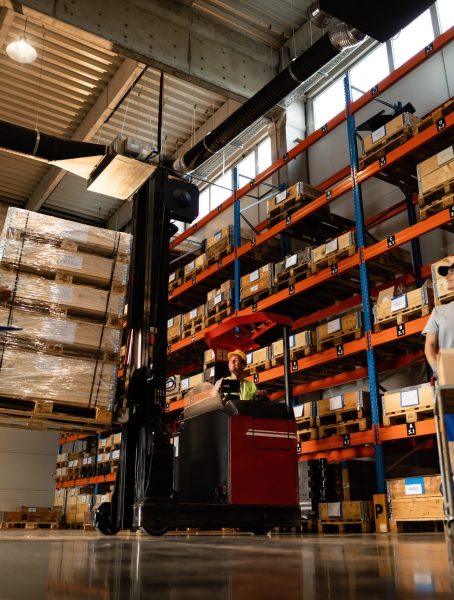 Low angle view of happy warehouse workers communicating while working with shipment in industrial storage compartment.
